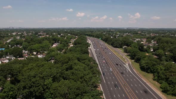 An aerial time lapse of a highway. It is a high angle shot showing the horizon and blue skies with w alt