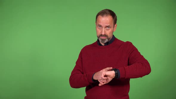 A Middleaged Caucasian Man Taps His Watch and Looks Sternly at the Camera  Green Screen