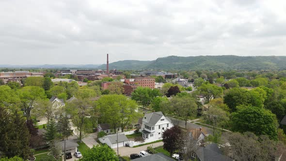 Midwest city in valley with mountains covered in trees with hazy sky. Birds flying in the sky.