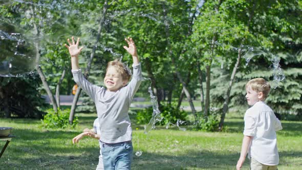 Adorable Little Boys Bursting Giant Soap Bubble during Performance alt