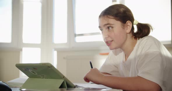 Girl Using Digital Tablet Technology Device in an Online Lesson Talking on Video Via Tablet alt