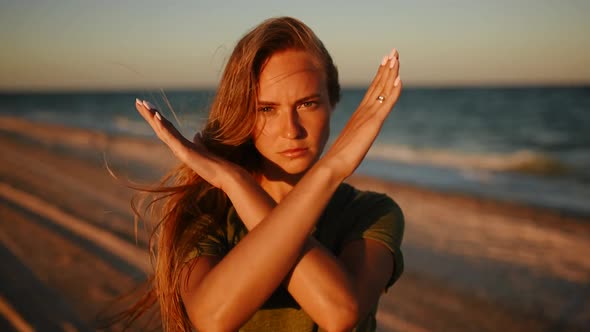 Serious Young Woman Showing Crossed Hands alt