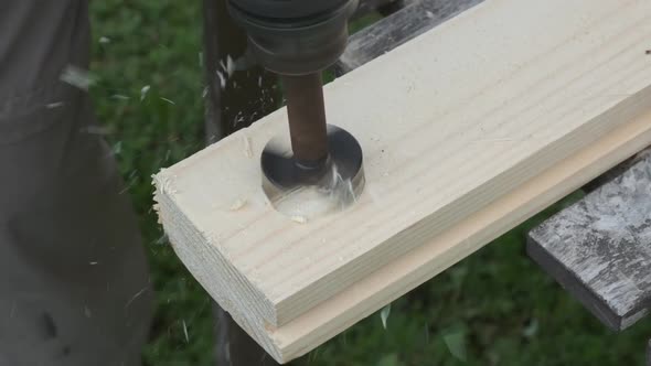 Closeup of a wood spade bit with number is drilling a hole on a high speed in a wooden plank