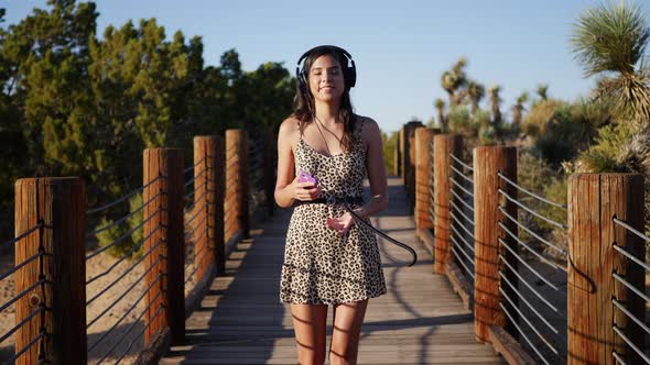 A beautiful young woman listening to music streaming from her smartphone on her headphones while wal alt