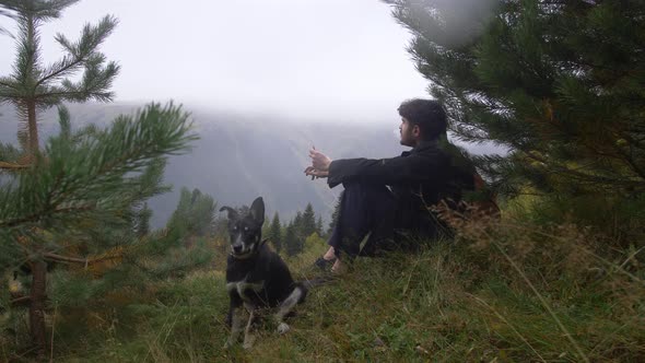 Alabai Breed Dog with a Young Guy on the Background of the Alpine Mountains a Pet Friendship with a