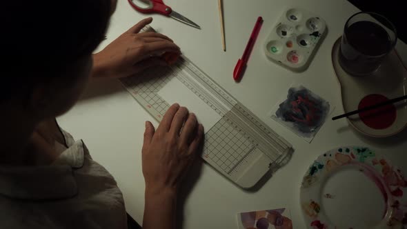 Young Woman Cuts a Piece of Cardboard for Creativity alt