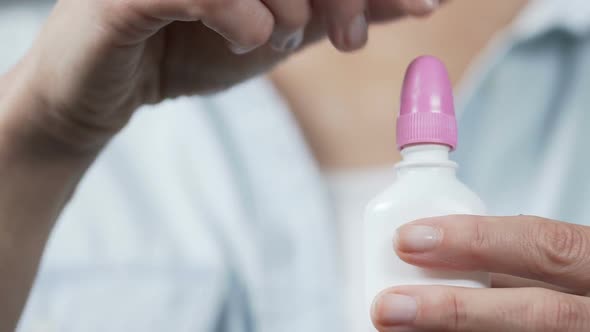 Hands of Woman Opening Bottle with Nasal Drops, Squeezing Bottle, Corked Nose alt