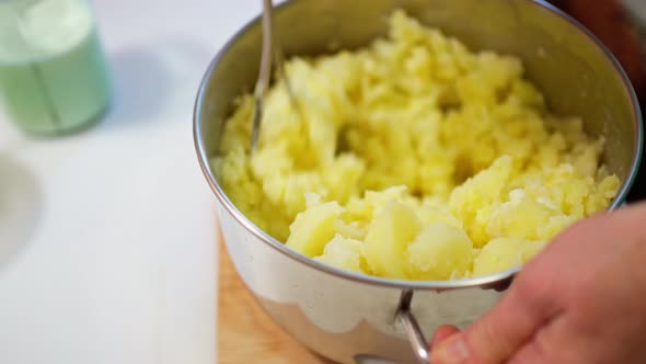 Female Hands Prepare Mashed Potatoes Mix Mashed Boiled Potatoes with a Crush alt