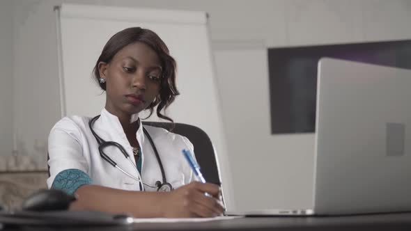 Medicine, People and Healthcare Concept - Happy Female African American Doctor or Nurse Writing alt