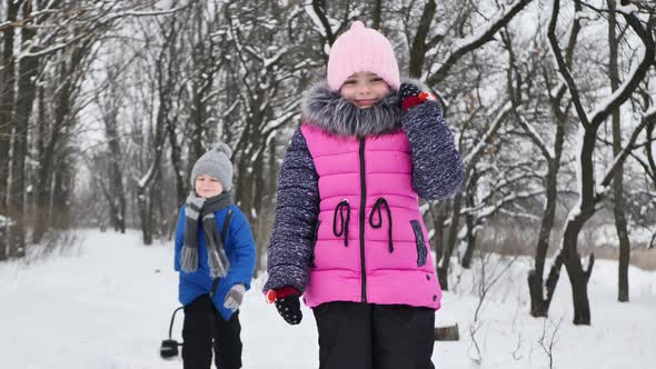 Children a Boy and a Girl in the Forest in Winter Jump Throw Snow and Laugh