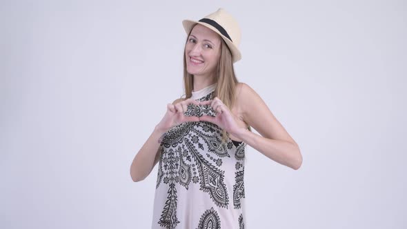 Portrait of Happy Blonde Tourist Woman with Hand Heart Gesture alt