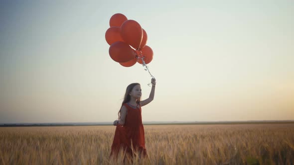Happy Young Girl with Balloons Running in the Wheat Field at Sunset  Video. alt