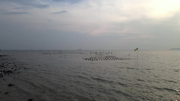 Drone flying towards the flag was hoisted on a rock in the middle of the sea