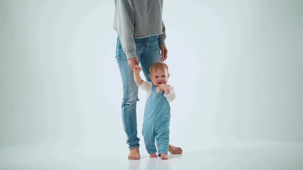 Mom holds the baby by the hand and teaches to walk. studio slow motion alt
