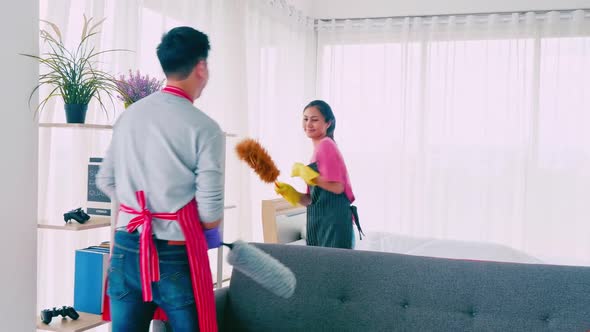 Husband and wife cleaning their room. Happy Asian couple spending time together at home. alt