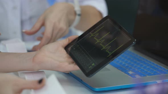 The Doctor Examines the Patient Cardiogram on Tablet the Nurse Writes the Advice of a Doctor