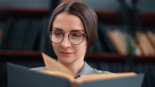 Closeup Smiling Woman in Eyeglasses Reading Book at Library Enjoy Literature Hobby Positive Emotion alt