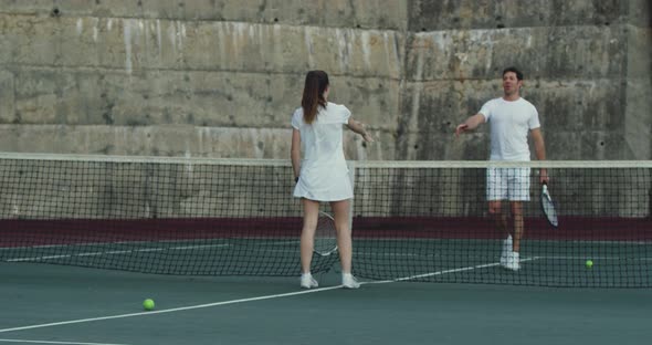 Woman and man playing tennis on a court alt