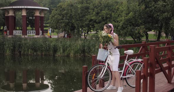 Woman in White Dress Looking at Camera While Riding in Park