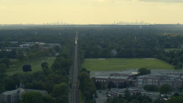 Aerial of a Train Passing Through Garden City and NYC Skyline Seen From Afar alt