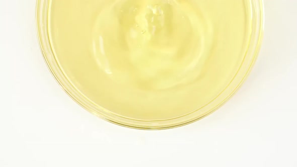 Slow Motion of Transparent Yellow Cosmetic Fluid Dripping Into the Glass Petri Dish alt