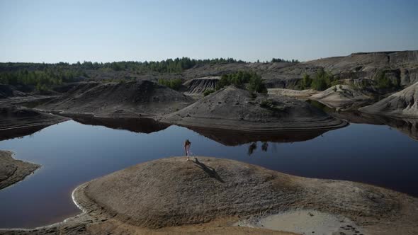 A Girl Sports on Top of a Sandy Mountain Among a Lot of Small Lakes