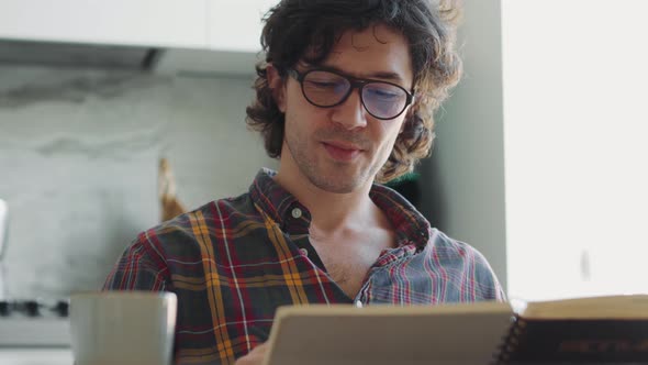 Positive adult man in a plaid shirt painting something in notepad alt