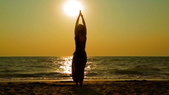 Girl Practicing Yoga On The Beach At Sunset
