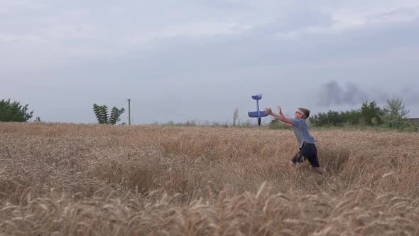 The guy is played with a toy airplane model on a wheat field. alt