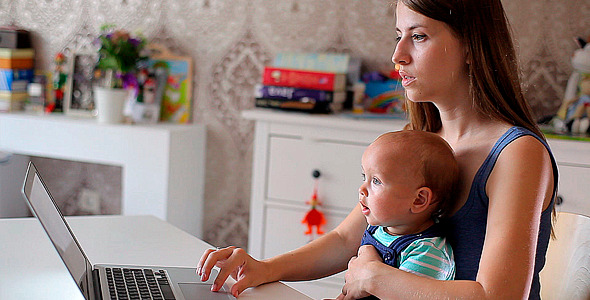 Young Mother with a Child Working at a Notebook