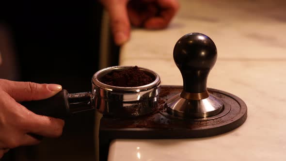 Coffee Grounds Espresso. Barista tamping (pressing) coffee grounds in portafilter (Espresso Machine)