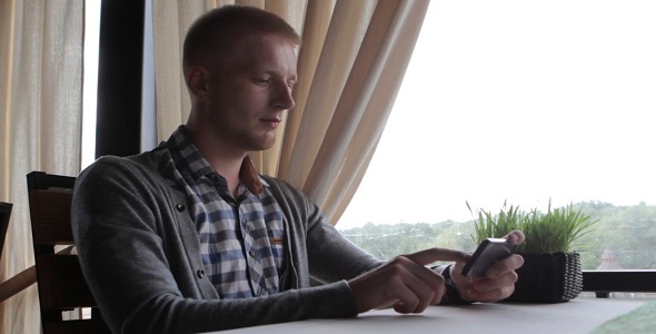 Young Guy Using Mobile Phone In The Restaurant Young Guy Using Mobile Phone In The Restaurant