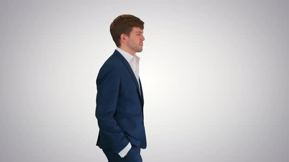 Young Confident Businessman Walking with His Hands in His Pockets on Gradient Background alt