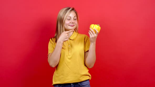 Cute and Slightly Fat Girl in a Yellow T-shirt Who Holds the Yellow Pepper in Her Hand alt