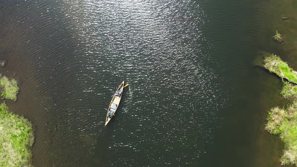 Top down drone shot of two people paddling a canoe in an estuary alt
