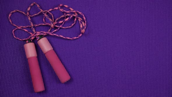 Unrolling Purple Yoga Mat and Pink Skipping Rope on it. Stop Motion alt
