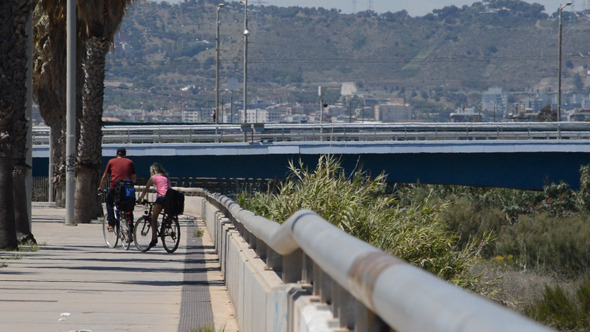 Man And Girl On Bikes Near A Road In The Sun Man And Girl On Bikes Near A Road In The Sun
