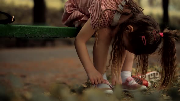 Kid  Sitting And Tying Sneakers Shoes. Children Sitting In Park And Preparing To Walk With Parents. alt