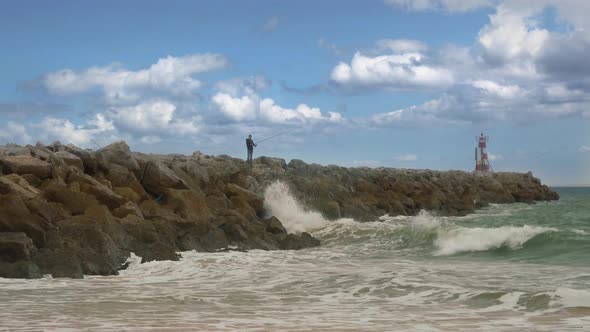 Fisherman on rocks fishing in the sea off the coast alt