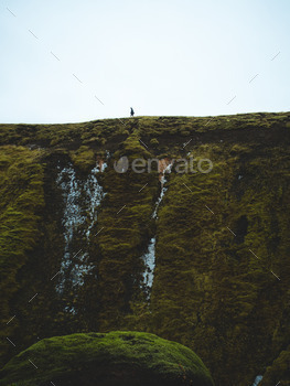 Man on a green ledge walking.