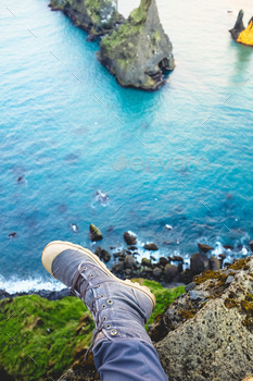 Feet dangling from ledge looking at rock formation