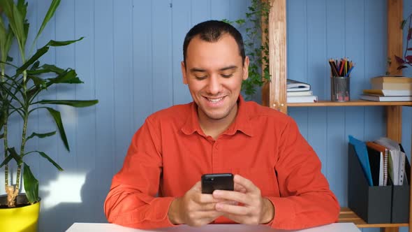 Young Man Holding Modern Smartphone Texting Message in Office