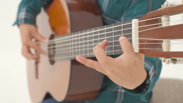Little Boy is Playing Big Classical Guitar Sitting on the Stool alt