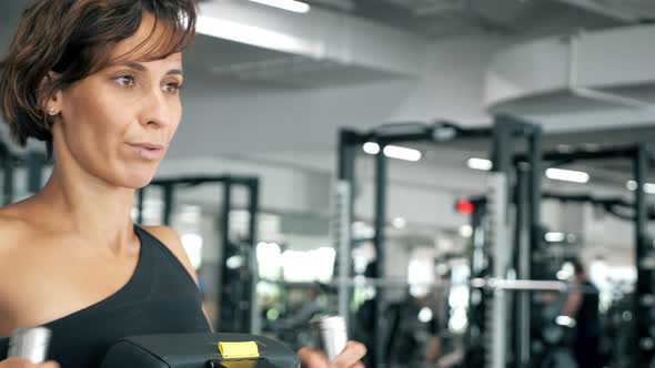 Portrait of Woman is Making Exercises for Spine Muscles on Rowing Machine alt