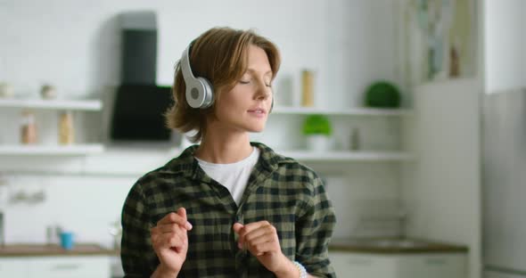 Woman in Positive Mood Is Listening Music in Wireless Headset, Close Up alt