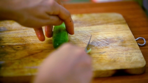 Female Hands Cutting Cucumber On Wooden Board.