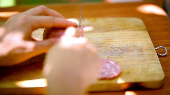 Female Hands Sliced Sausage On a Wooden Cutting