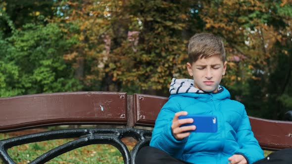 Boy Sits On Bench In A Park alt