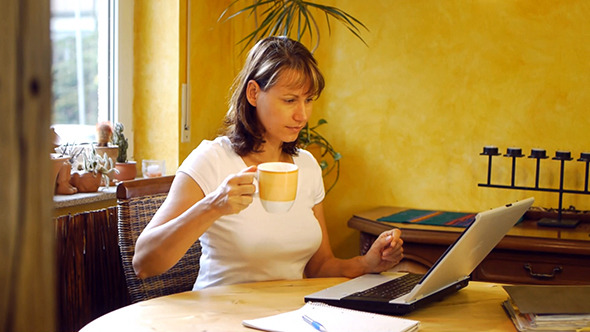 Young Woman Using Laptop And Drinking Coffee