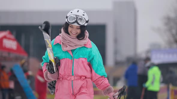 Excited Woman with Toothy Smile in Ski Suit with Skiing Equipment Walking in Slow Motion Looking alt